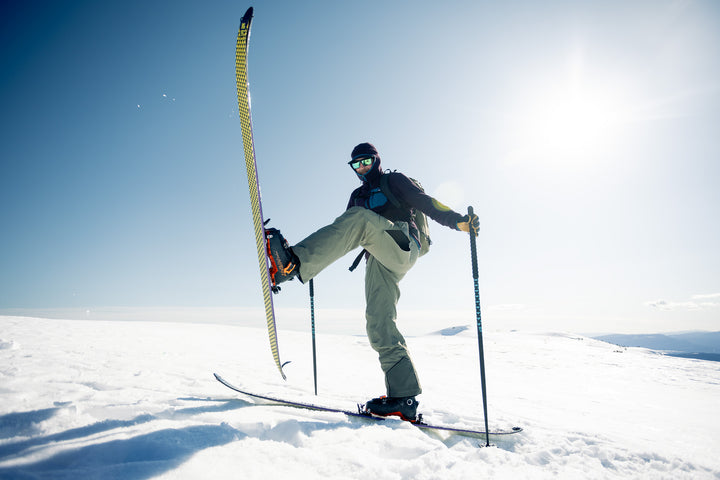 Person skiing with one ski lifted in the air on a snowy landscape